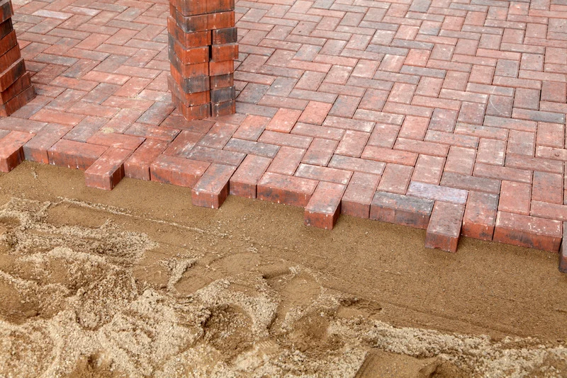 Red brick interlock pavers laid in a herringbone pattern with sand joints, Ottawa.