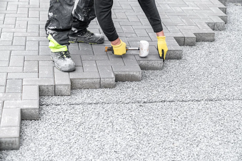 Installer setting interlock pavers with a rubber mallet during an Ottawa driveway installation.