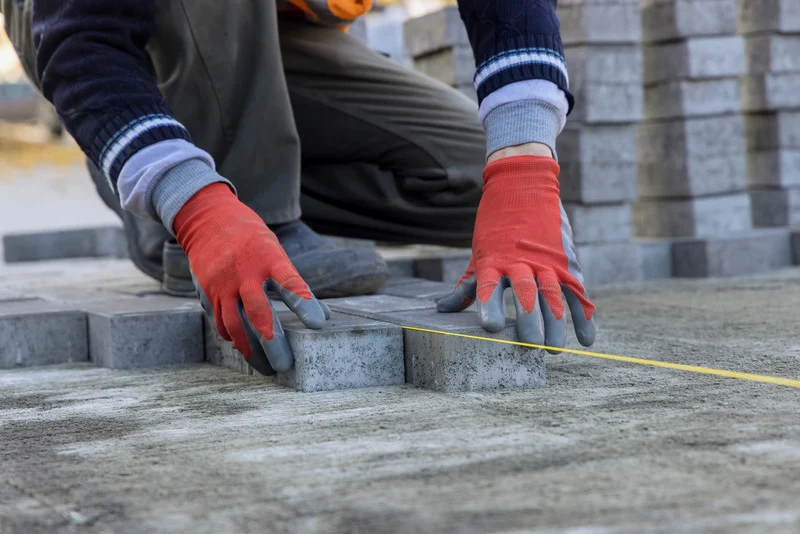 An installer places interlocking paving stones onto a compacted base as part of an Ottawa paver patio installation.