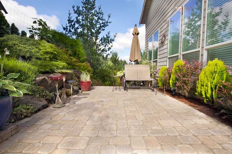 A finished Ottawa paver patio with furniture and an umbrella creates a functional outdoor living space.