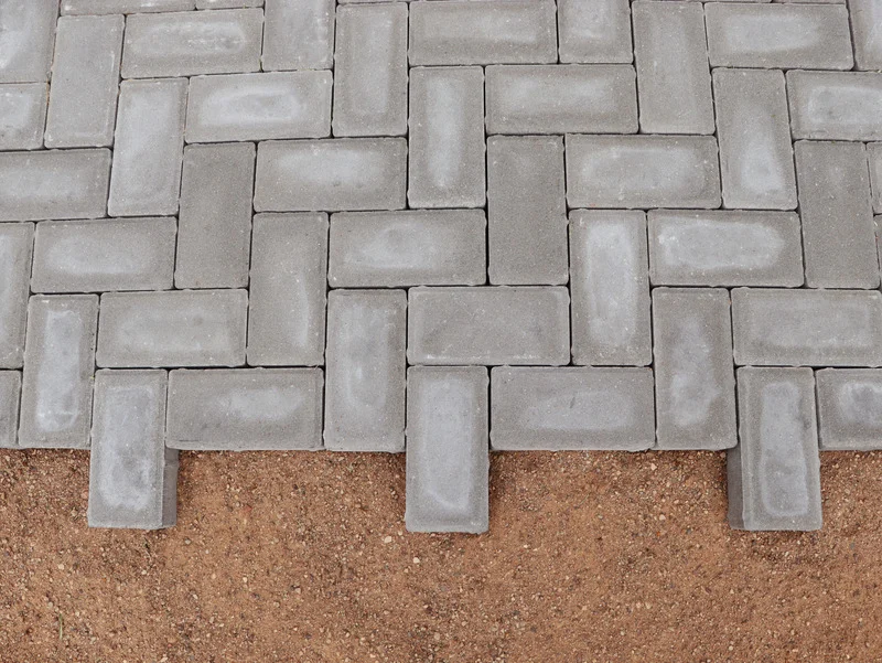 A close-up herringbone pattern shows the layout style used on an Ottawa paver patio installation.