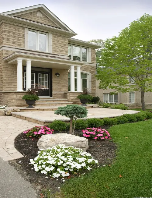Stone-front Ottawa home with a curved paver walkway and boulder garden bed, an example of residential landscape construction by KJ Landscape & Design.